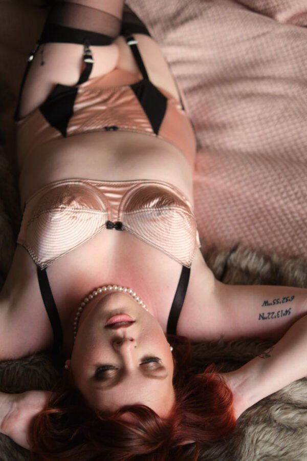 redhead woman lying down in in two piece lingerie set with pearls plus size